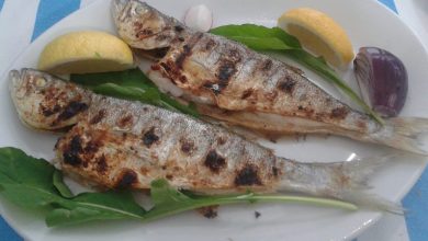 Izgara balik, limon ve yesillikle tabakta servis edilmis