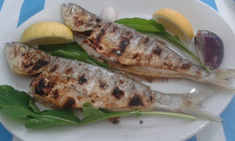 Izgara balik, limon ve yesillikle tabakta servis edilmis